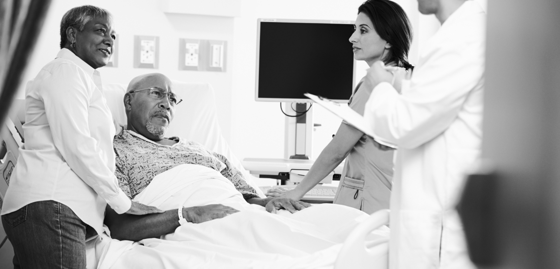 Myeloma patient in hospital bed, talking with spouse, doctor, and nurse.